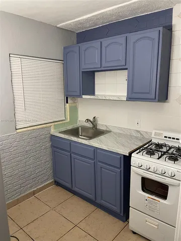 a kitchen with granite countertop a sink stove and cabinets