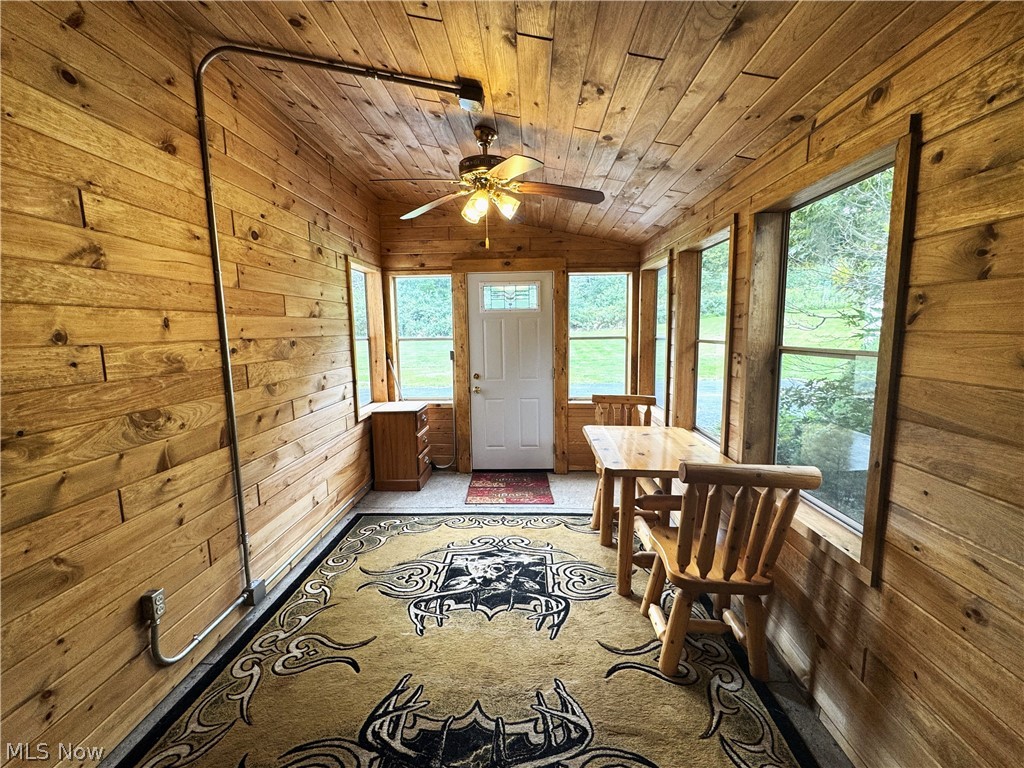 4421 State Road South Ashtabula, OH 44004 - Photo 5 of 18 Wood-paneled walls and ceiling, multiple windows, ceiling fan, and a paneled entry door with transom window