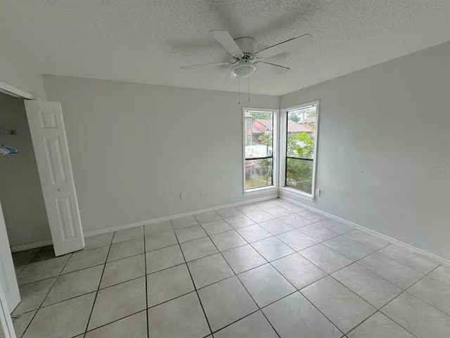 an empty room with windows and fan
