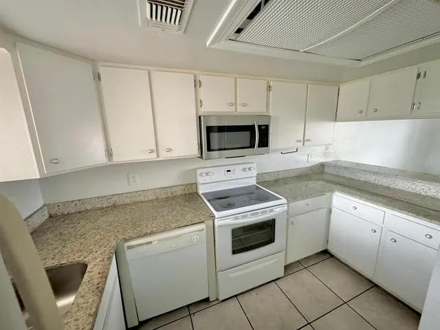 a kitchen with granite countertop white cabinets and white appliances