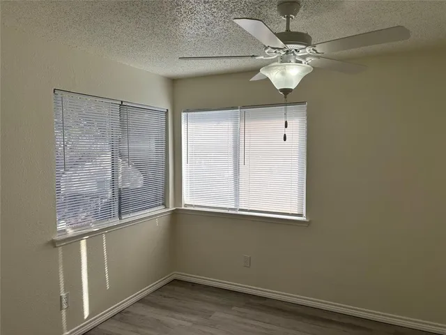 an empty room with a window and a chandelier fan