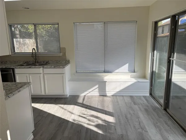a kitchen with granite countertop a refrigerator a sink and white cabinets