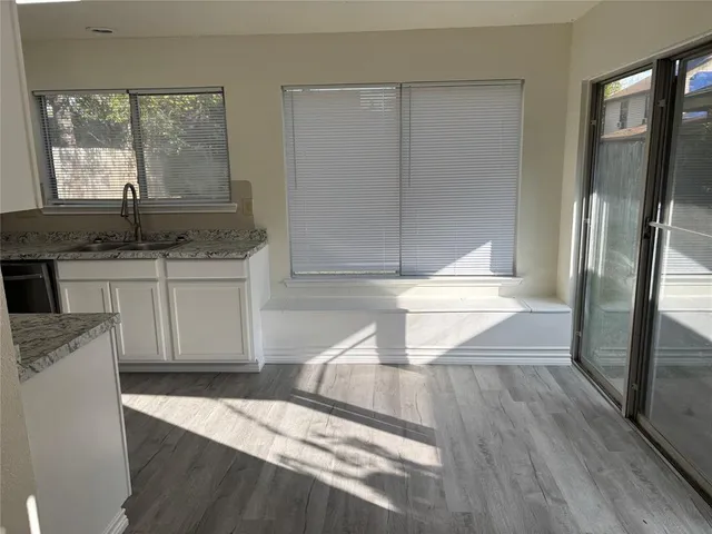 a kitchen with granite countertop a refrigerator a sink and white cabinets
