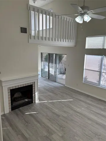 a view of an empty room with chandelier fan and fire place