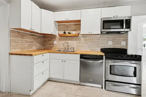 a kitchen with stainless steel appliances a stove microwave and sink