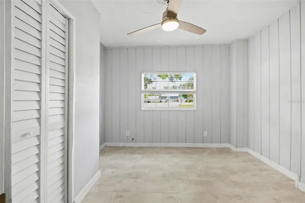 an empty room with windows and ceiling fan