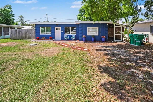 a view of a house with a yard and large tree