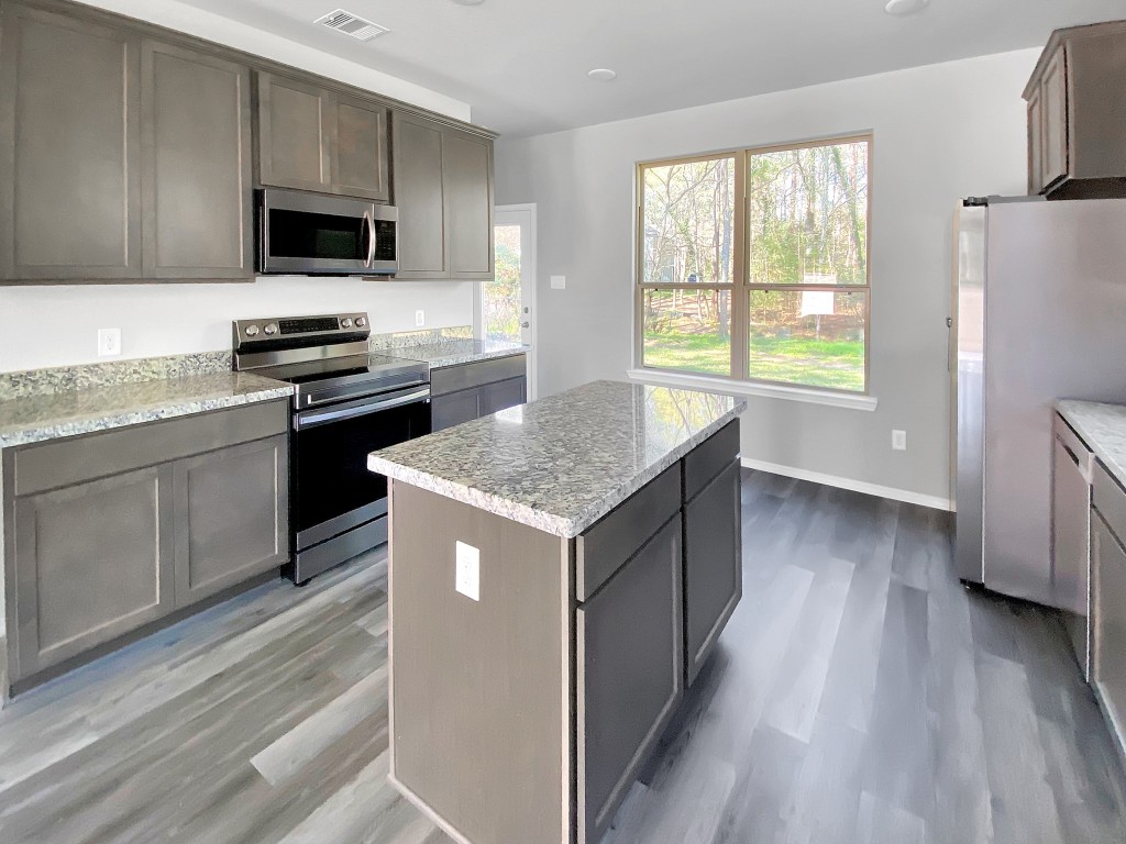 1202 St Lawrence River Road Montgomery, TX 77316 - Photo 7 of 21 a kitchen with kitchen island granite countertop a stove top oven a sink dishwasher a refrigerator and a stove with wooden floor