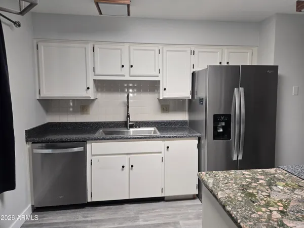 a kitchen with granite countertop white cabinets and stainless steel appliances