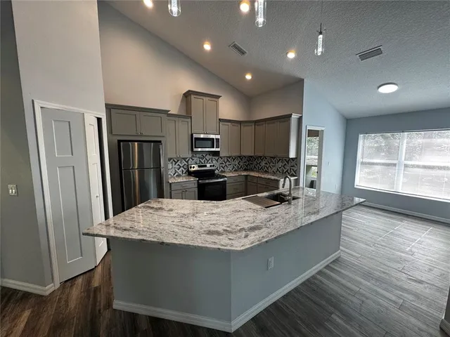 a kitchen with kitchen island a sink appliances and wooden floor