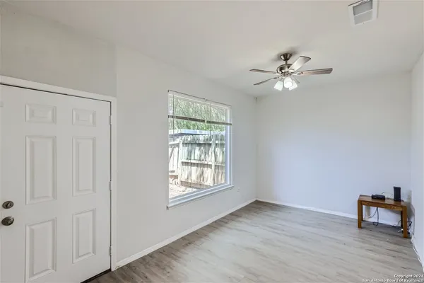 a view of an empty room with a window and wooden floor