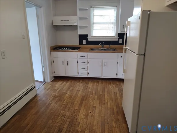 a kitchen with granite countertop a refrigerator a sink and wooden floors