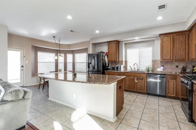 a large kitchen with kitchen island granite countertop a large counter top and stainless steel appliances
