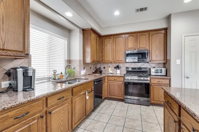 a kitchen with stainless steel appliances granite countertop a sink a stove a microwave and cabinets