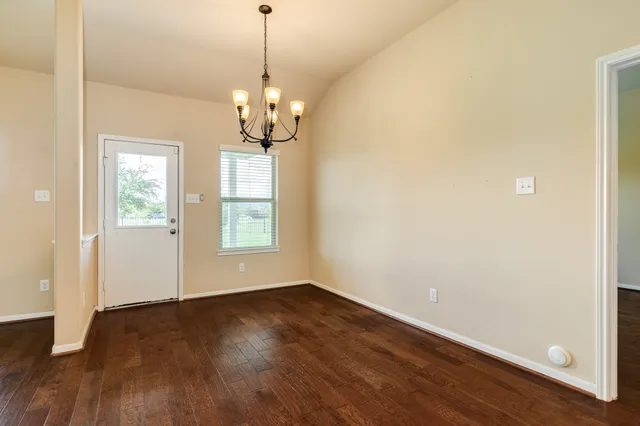 a view of a room with wooden floor chandelier and a window