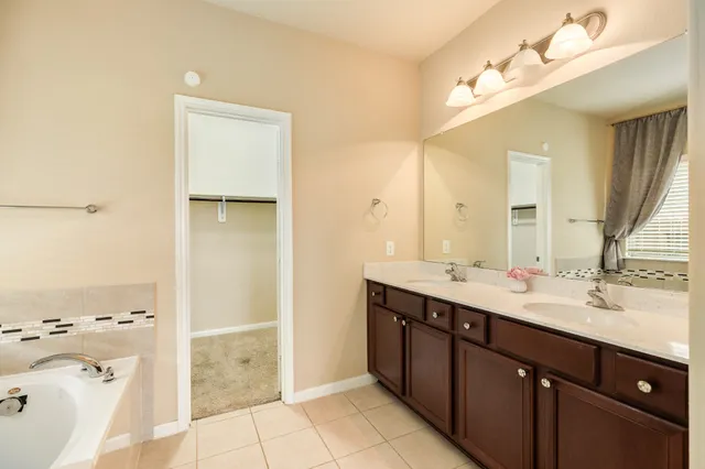 a en suite bathroom with a double vanity sink a mirror and a bathtub
