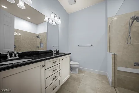 a bathroom with a granite countertop sink a toilet a mirror and shower