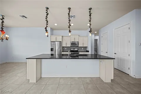 a large kitchen with granite countertop a white cabinets and stainless steel appliances