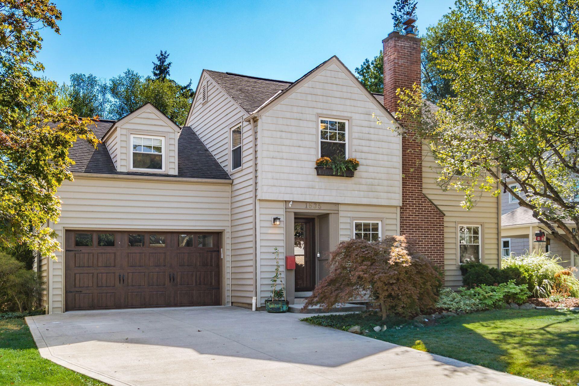 Elegant curb appeal with mature shade trees, lush green grass, and a beautifully manicured lawn creating a welcoming entrance.