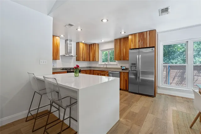 a kitchen with stainless steel appliances a refrigerator a stove a sink cabinets and a dining table