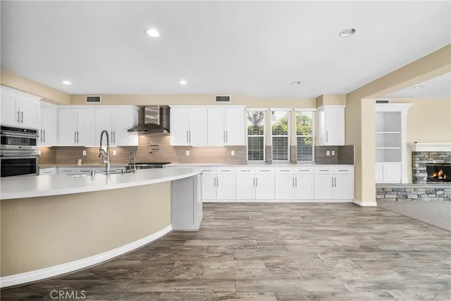 a large kitchen with cabinets wooden floor and stainless steel appliances