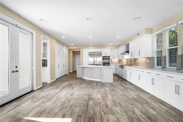a view of kitchen with stainless steel appliances granite countertop a stove top oven a sink and a refrigerator