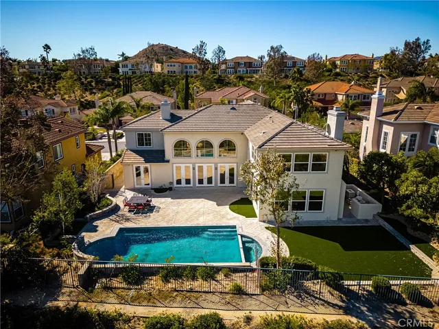 a view of a white house with a yard plants and large tree