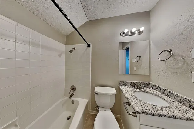 a bathroom with a granite countertop sink a toilet and bathtub