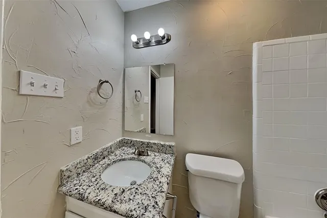 a bathroom with a granite countertop sink a toilet and mirror