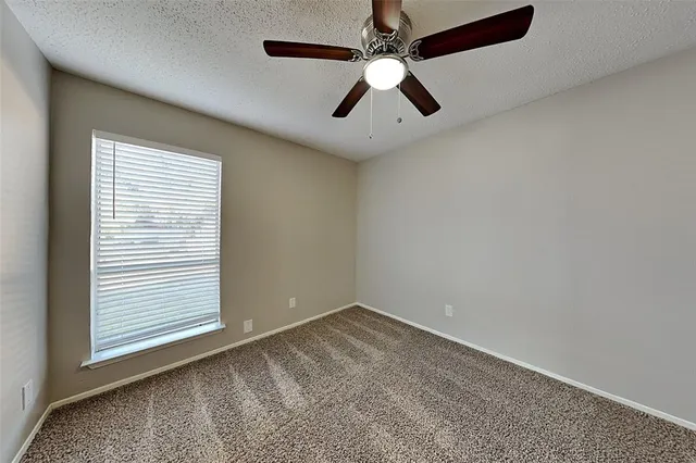 an empty room with a window and a fan