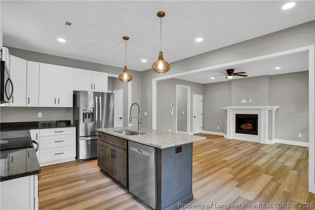 610 North Main Street Raeford, NC 28376 - Photo 11 of 28 a large kitchen with granite countertop a stove top oven a sink dishwasher and a fireplace with wooden floor