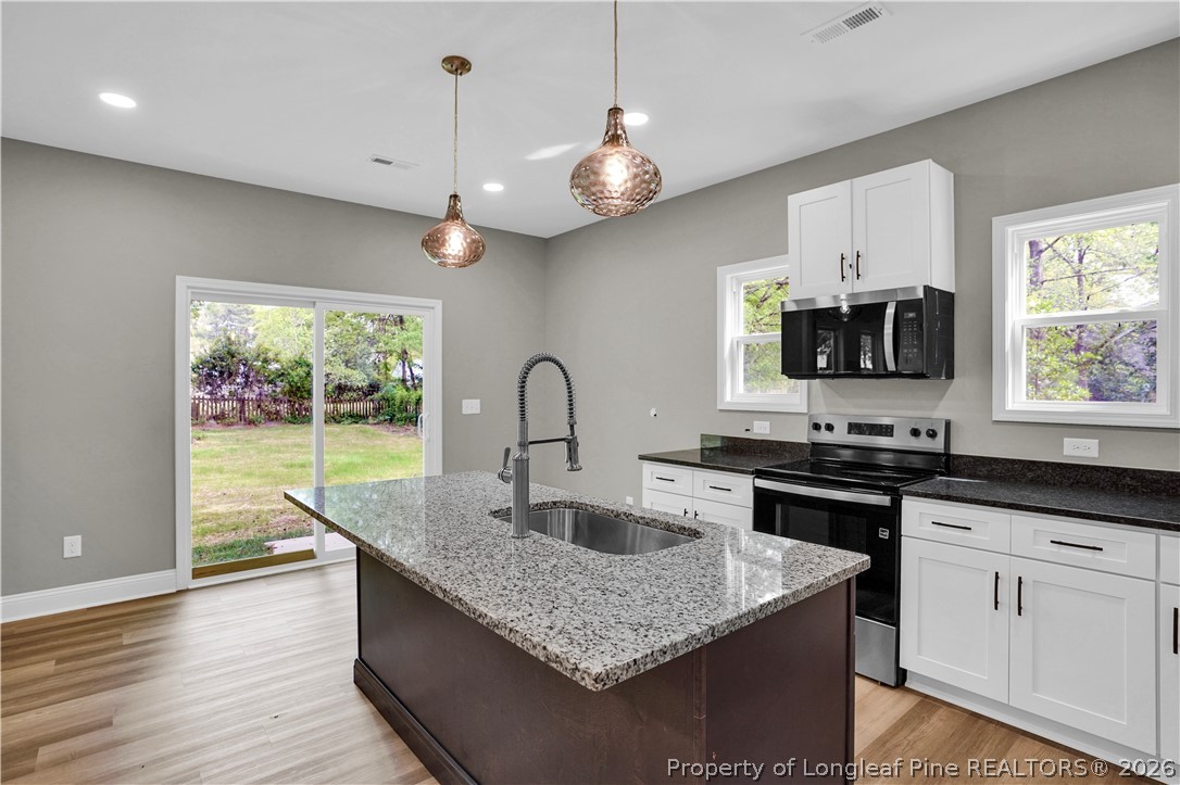 610 North Main Street Raeford, NC 28376 - Photo 9 of 28 a kitchen with granite countertop a stove a sink and dishwasher with wooden floor