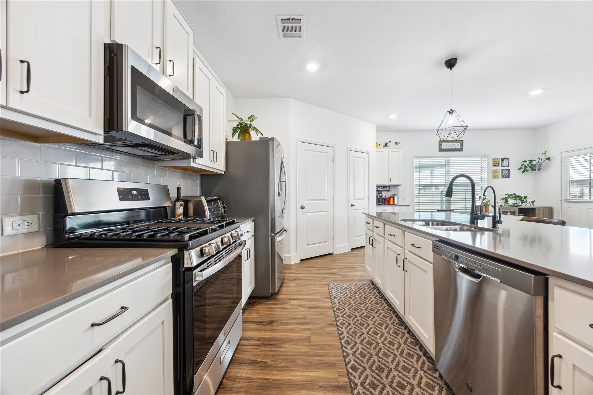 700 Legends Lane Georgetown, TX 78628 - Photo 7 of 31 Kitchen with appliances with stainless steel finishes, a sink, wood finished floors, decorative backsplash, and white cabinetry