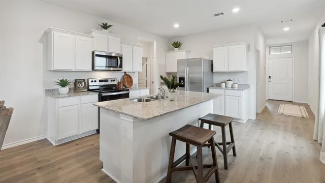 a kitchen with a sink a microwave a refrigerator and white cabinets