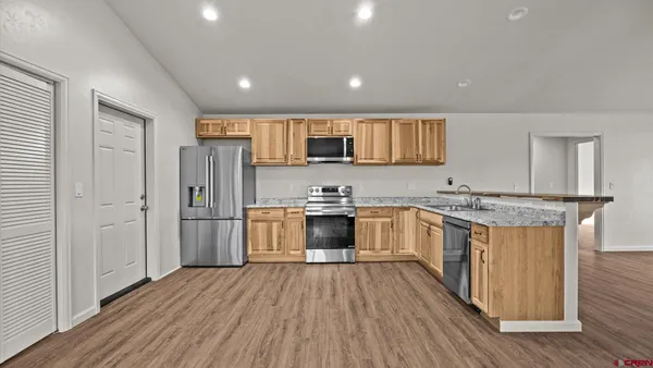a kitchen with stainless steel appliances granite countertop a refrigerator a stove top oven a sink dishwasher and a refrigerator with wooden floor