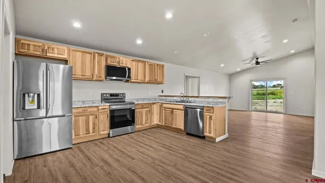a view of kitchen with stainless steel appliances granite countertop cabinets and wooden floor