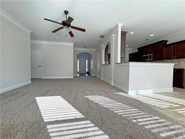 a view of an empty room with kitchen and a window
