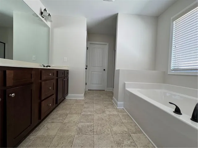 a spacious bathroom with a tub sink and mirror