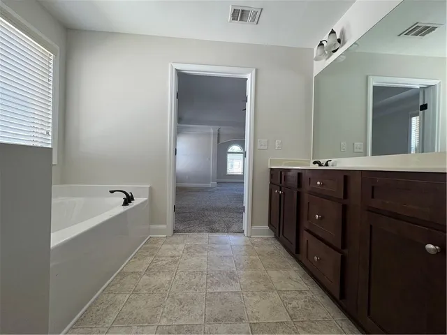 a spacious bathroom with a tub sink shower and mirror