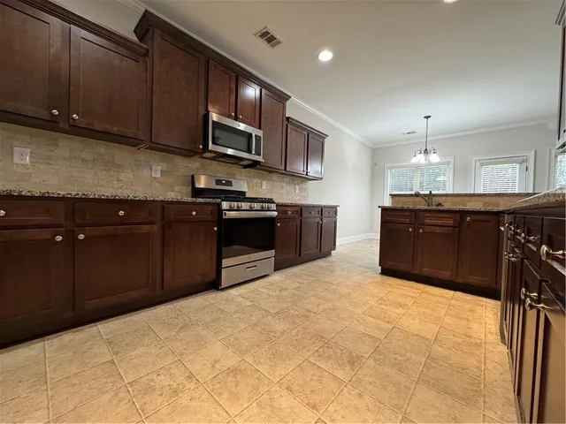a kitchen with stainless steel appliances granite countertop a stove a sink dishwasher and a refrigerator