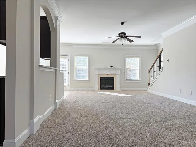 a view of an empty room with chandelier fan and fire place