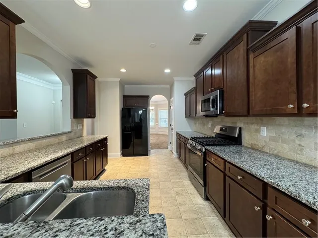 a kitchen with stainless steel appliances granite countertop a sink a stove and a wooden cabinets