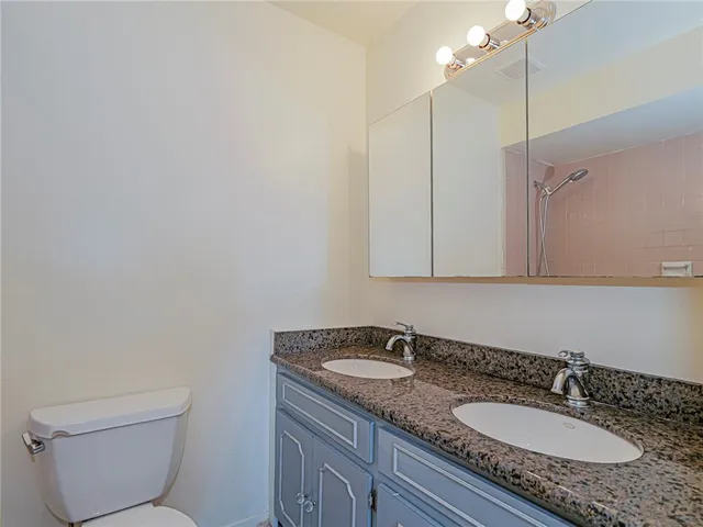 a bathroom with a granite countertop sink a toilet and mirror