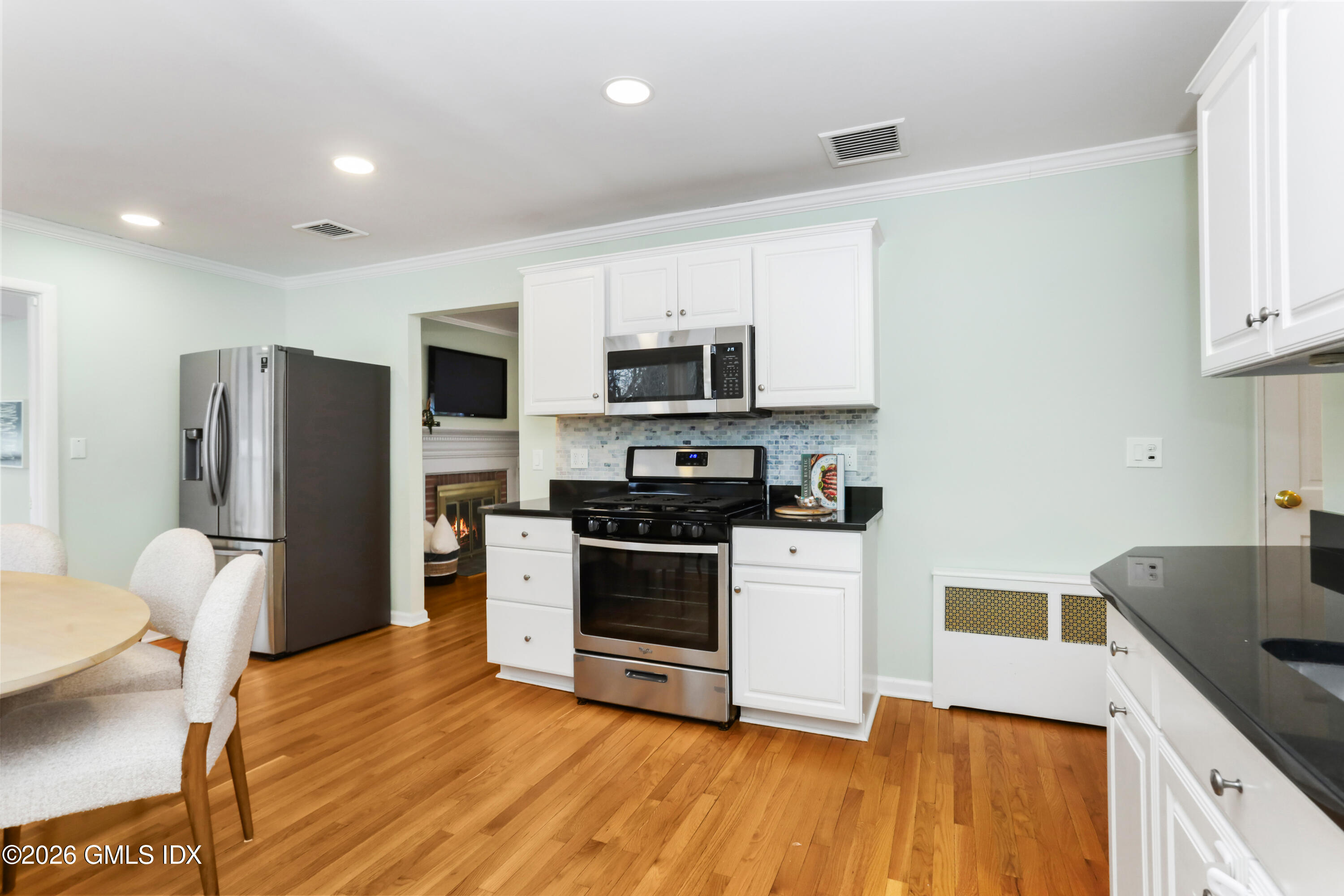 45 Sound Beach Ave Extension Riverside, CT 06878 - Photo 7 of 31 a kitchen with stainless steel appliances a stove a sink a refrigerator white cabinets and wooden floor