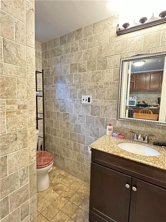467 56th Street Brooklyn, NY 11220 - Photo 4 of 8 a bathroom with a granite countertop toilet a sink and a mirror
