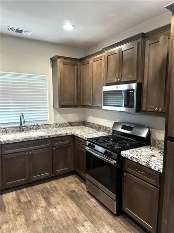 a kitchen with granite countertop wooden cabinets and a stove top oven