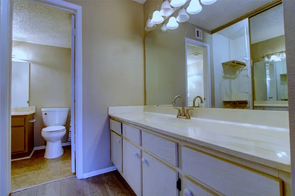 a bathroom with a granite countertop sink a toilet and a mirror