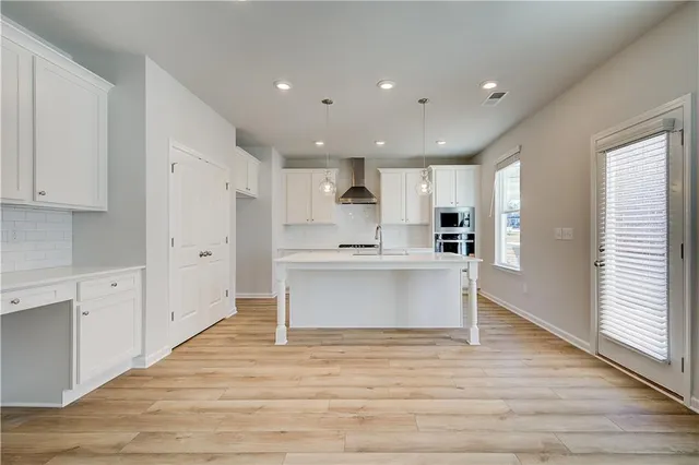 a view of kitchen with kitchen island sink refrigerator and white cabinets