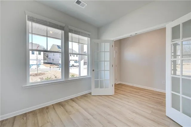an empty room with wooden floor and windows