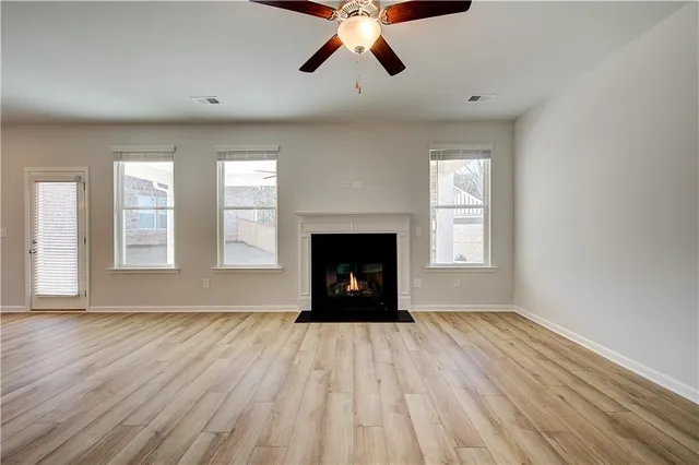 a view of an empty room with wooden floor fireplace and a window